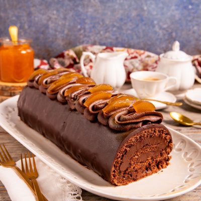 Tronchetto Sacher glassato al cioccolato con ciuffi di crema e scorze di arancia candita