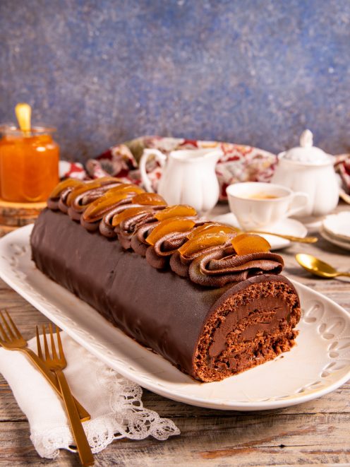 Tronchetto Sacher glassato al cioccolato con ciuffi di crema e scorze di arancia candita