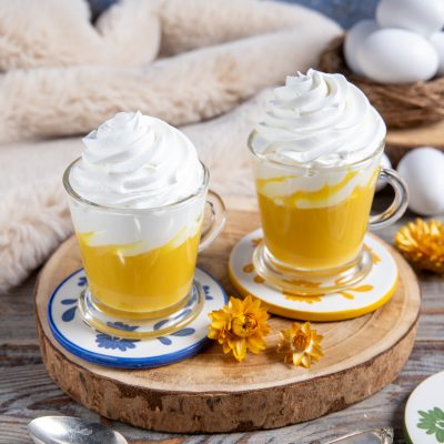 Bombardino servito in due bicchieri con crema gialla all'uovo e ciuffo di panna montata