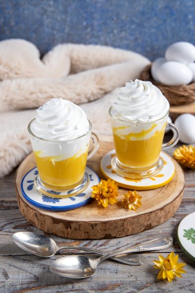 Bombardino servito in due bicchieri con crema gialla all'uovo e ciuffo di panna montata
