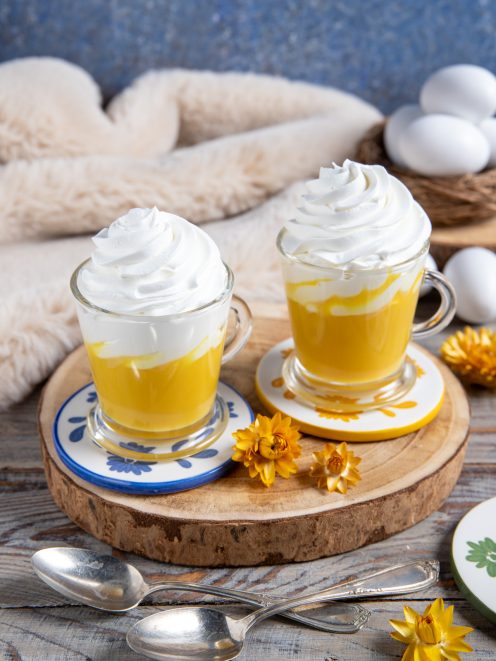 Bombardino servito in due bicchieri con crema gialla all'uovo e ciuffo di panna montata