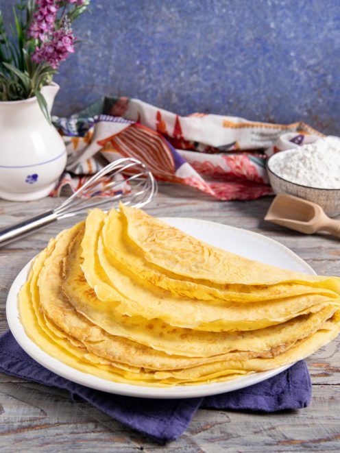 Crepes senza uova piegate a metà e impilate, dorate e sottili