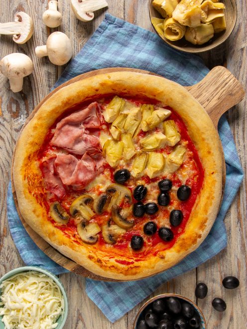 Pizza quattro stagioni con prosciutto cotto, carciofi, funghi e olive nere su salsa di pomodoro