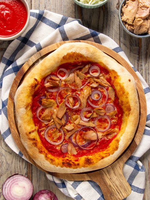 Pizza con tonno e cipolle rosse su salsa di pomodoro, con bordo dorato e croccante
