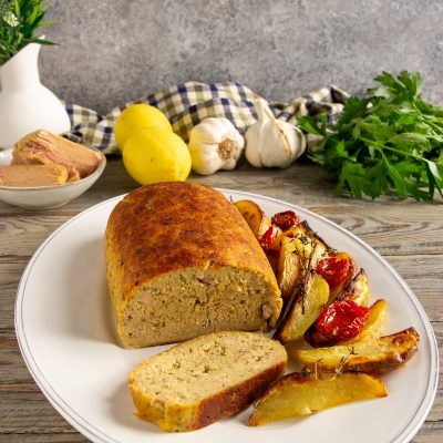 Polpettone di tonno affettato servito con patate al forno e pomodorini arrostiti