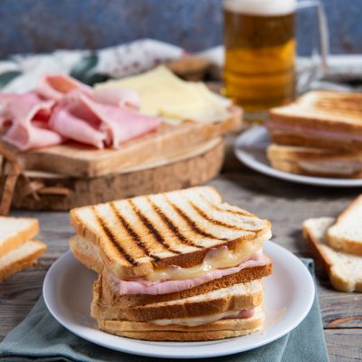Toast alla piastra con prosciutto cotto e formaggio filante, servito a metà