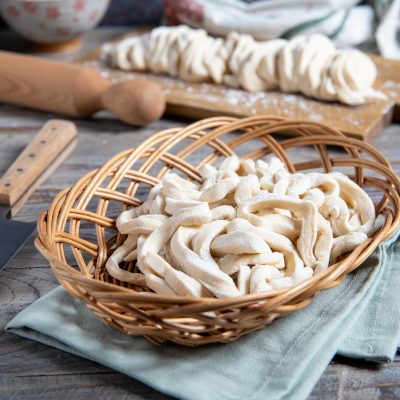 Udon freschi appena tagliati raccolti in un cestino, con altri sfilacci di pasta sullo sfondo