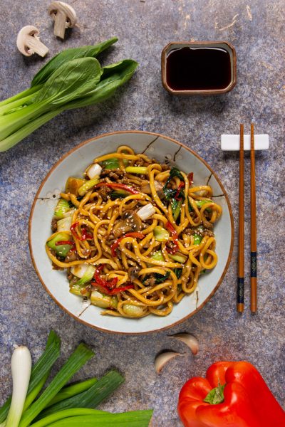 Yaki udon saltati con carne macinata, bok choy, peperoni rossi e semi di sesamo