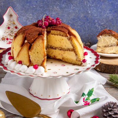 Zuccotto di pandoro a cupola tagliato a spicchi, farcito di crema e spolverato di cacao con ribes rosso