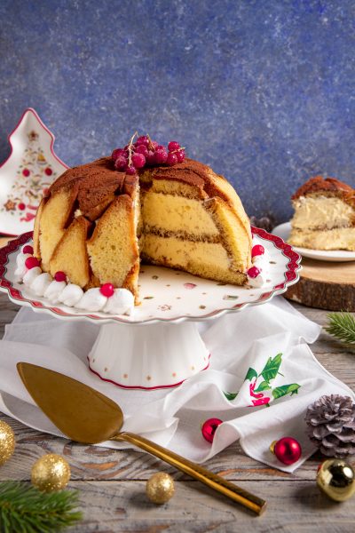 Zuccotto di pandoro a cupola tagliato a spicchi, farcito di crema e spolverato di cacao con ribes rosso