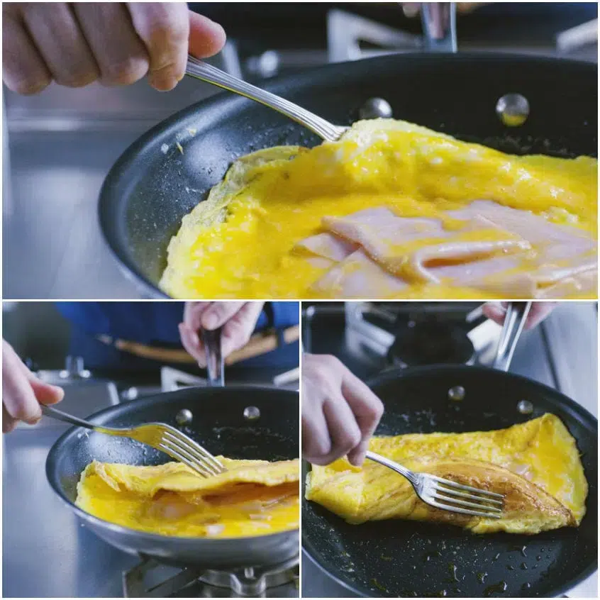 Omelette con prosciutto ripiegata in padella con l'aiuto di una forchetta