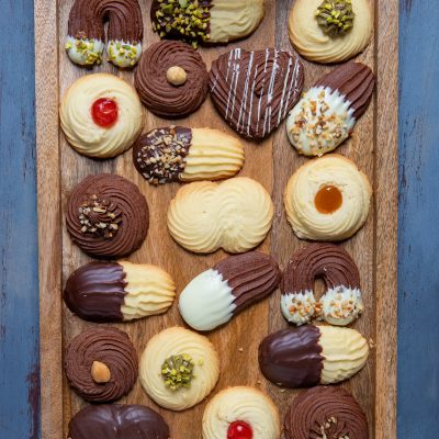 Biscotti di frolla montata assortiti con cioccolato fondente, bianco, pistacchi e ciliegine