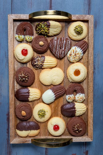 Biscotti di frolla montata assortiti con cioccolato fondente, bianco, pistacchi e ciliegine