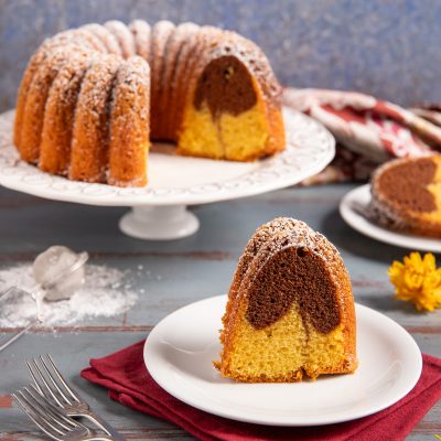 Ciambella bicolore con impasto vaniglia e cacao, spolverata di zucchero a velo, servita a fette