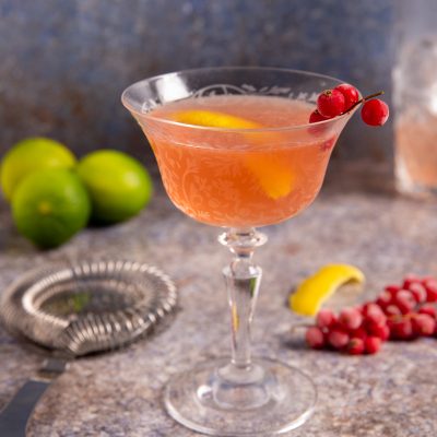 Cosmopolitan rosa servito in coppa con scorza di limone e ribes rosso sul bordo