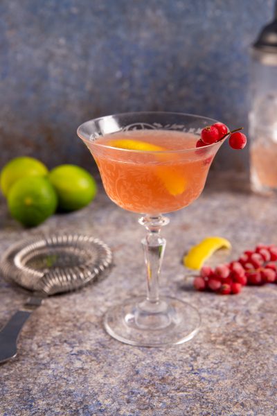 Cosmopolitan rosa servito in coppa con scorza di limone e ribes rosso sul bordo