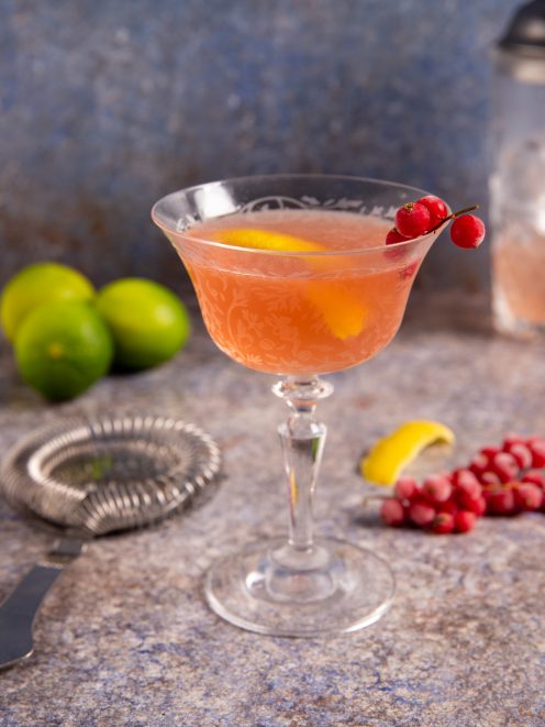 Cosmopolitan rosa servito in coppa con scorza di limone e ribes rosso sul bordo