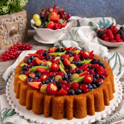 Crostata morbida con frutta guarnita da fragole, mirtilli, lamponi, ribes e uva