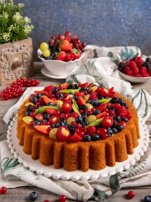 Crostata morbida con frutta guarnita da fragole, mirtilli, lamponi, ribes e uva