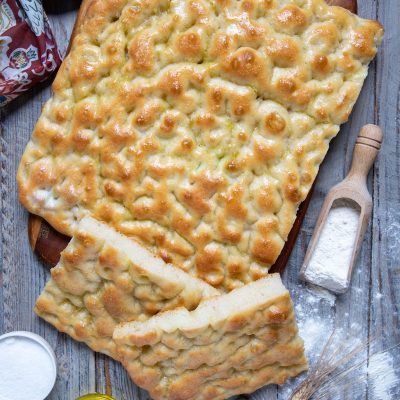 Focaccia ligure dorata con superficie a fossette lucida di olio, tagliata a strisce