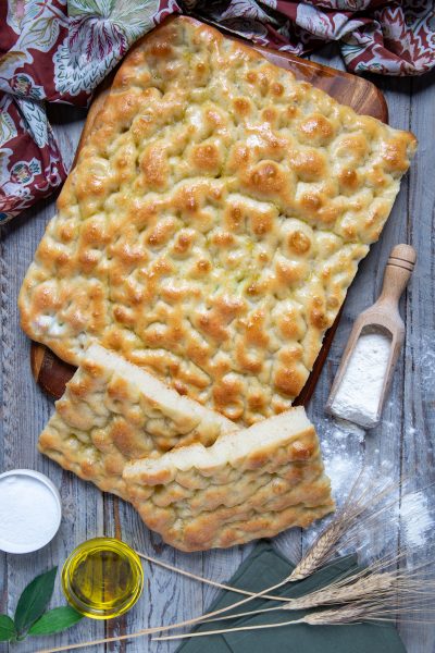 Focaccia ligure dorata con superficie a fossette lucida di olio, tagliata a strisce