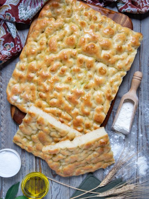 Focaccia ligure dorata con superficie a fossette lucida di olio, tagliata a strisce