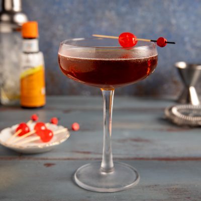 Manhattan cocktail in coppa con ciliegia al maraschino infilzata su stecchino