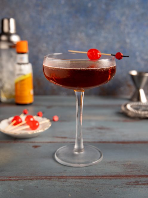 Manhattan cocktail in coppa con ciliegia al maraschino infilzata su stecchino