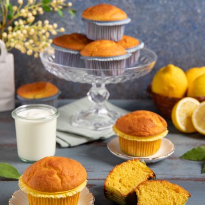 Muffin allo yogurt con cupola dorata, uno spezzato mostra la mollica soffice e compatta