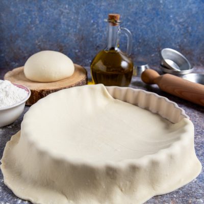 Pasta matta stesa a foderare uno stampo scanalato, con i bordi che ricadono all'esterno