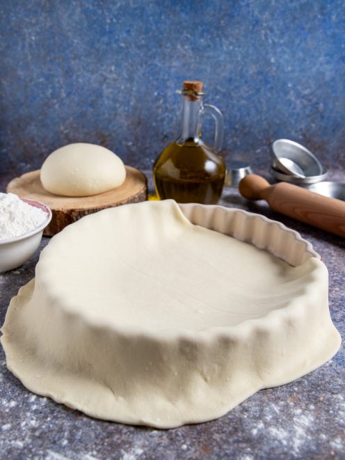 Pasta matta stesa a foderare uno stampo scanalato, con i bordi che ricadono all'esterno