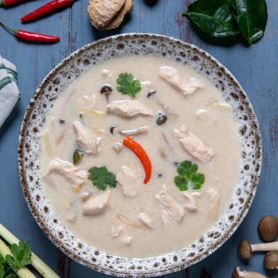 Tom kha gai con pollo, funghi e peperoncino in brodo cremoso di cocco, guarnito con coriandolo fresco