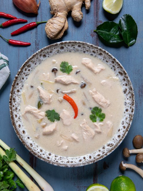 Tom kha gai con pollo, funghi e peperoncino in brodo cremoso di cocco, guarnito con coriandolo fresco