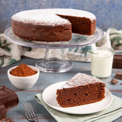 Torta allo yogurt e cioccolato spolverata di zucchero a velo, con una fetta servita sul piatto