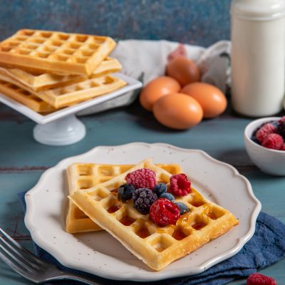 Waffle senza glutine guarniti con lamponi, mirtilli e sciroppo di miele