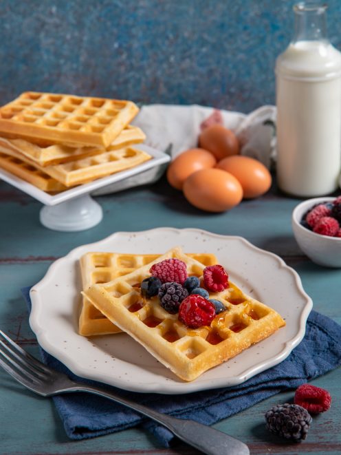 Waffle senza glutine guarniti con lamponi, mirtilli e sciroppo di miele