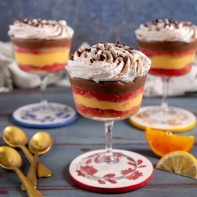 Zuppa inglese nel bicchiere con strati di crema gialla, alchermes e cioccolato, sormontata da panna e scaglie di cioccolato