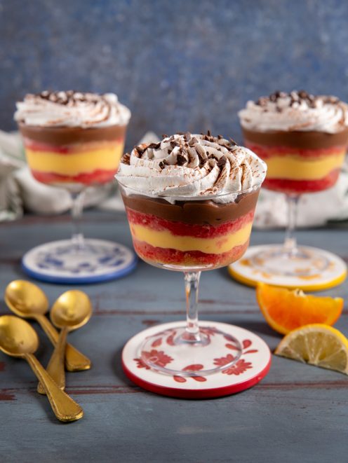 Zuppa inglese nel bicchiere con strati di crema gialla, alchermes e cioccolato, sormontata da panna e scaglie di cioccolato