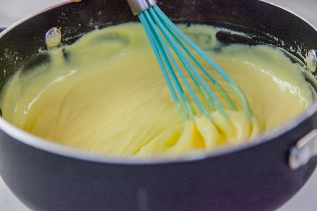 Crema catalana densa e lucida mescolata con una frusta in un pentolino