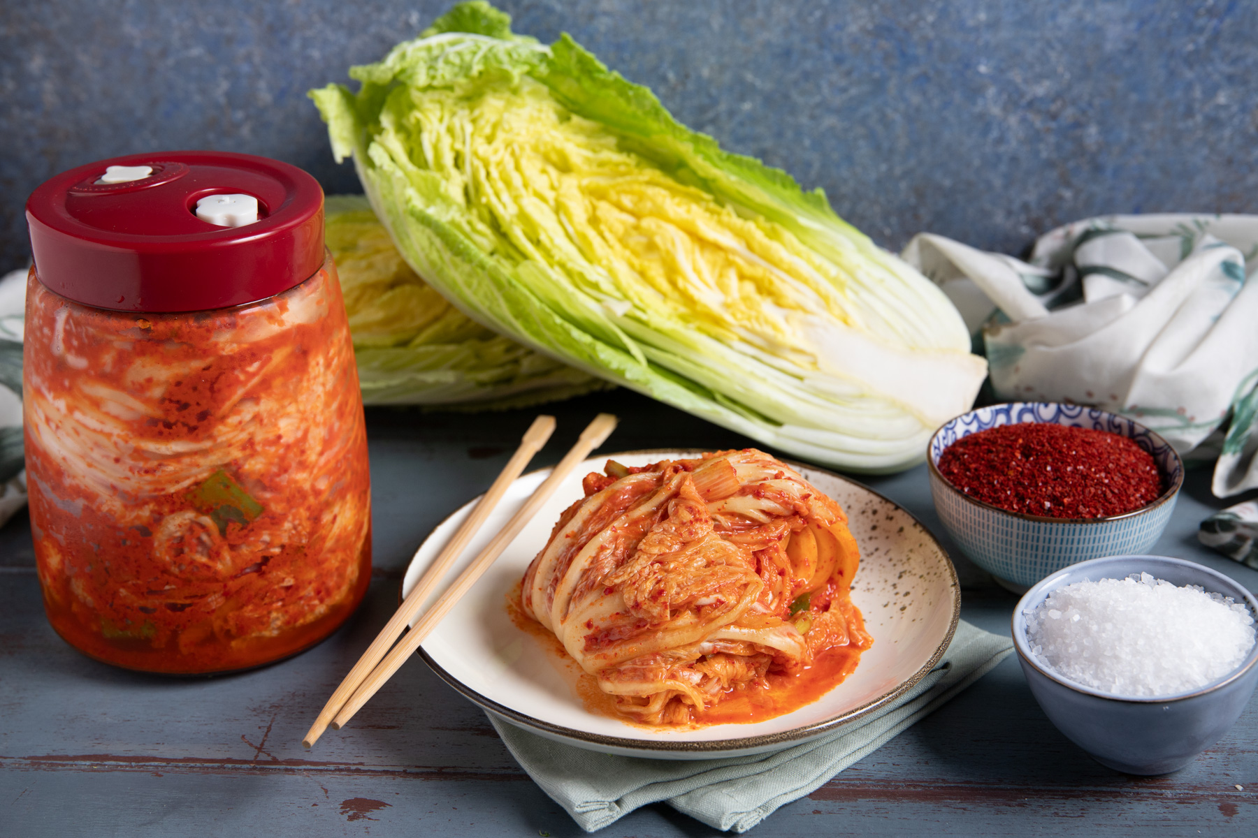 Kimchi pronto nel barattolo di fermentazione accanto a una porzione servita con bacchette