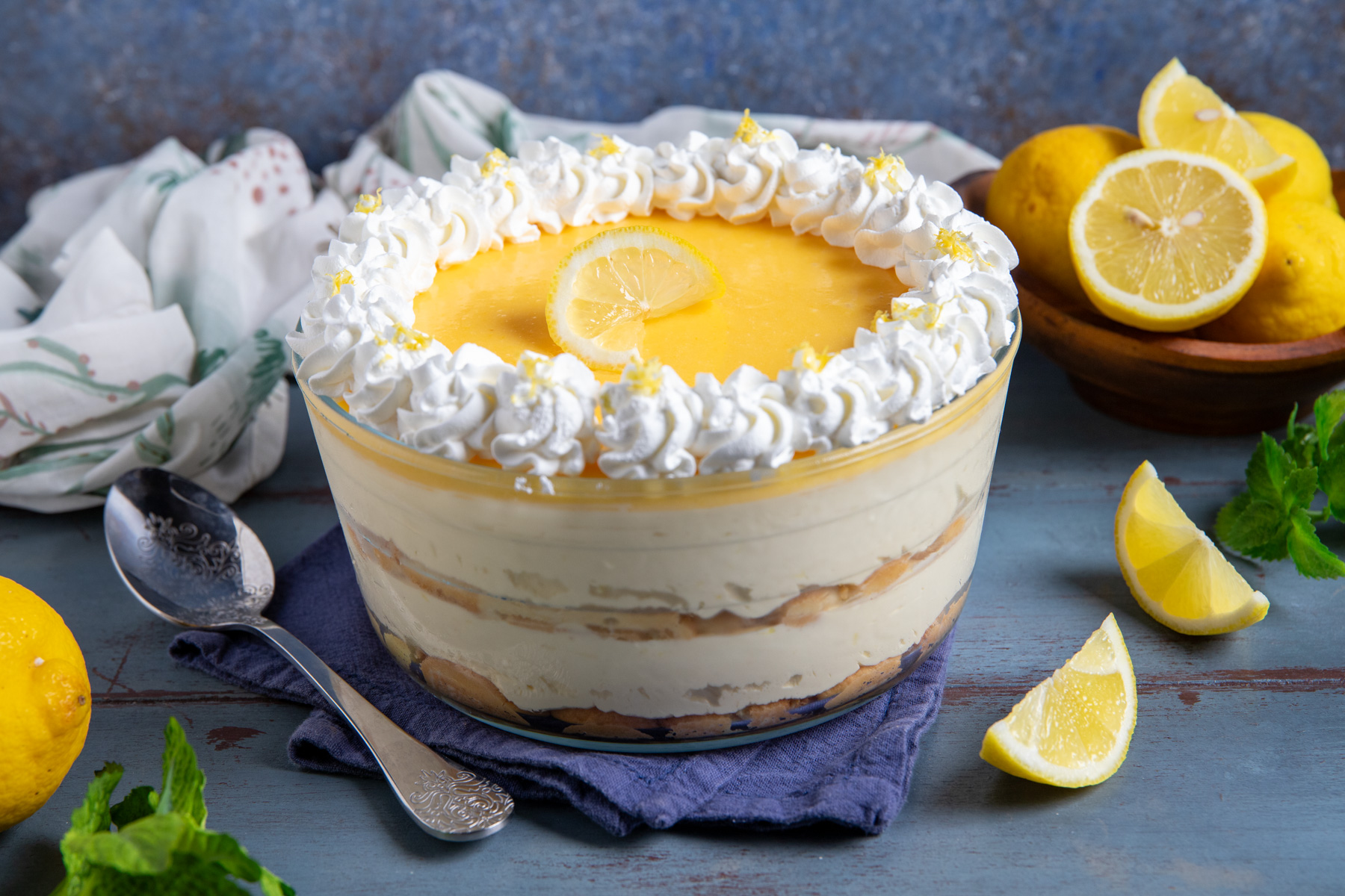 Tiramisù al limone a strati con crema, curd e ciuffi di panna montata, decorato con una fettina di limone al centro