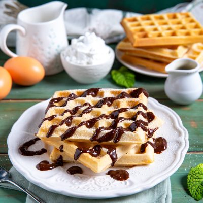 Waffle impilati con colata di salsa al cioccolato e zucchero a velo