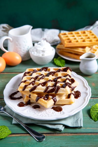 Waffle impilati con colata di salsa al cioccolato e zucchero a velo
