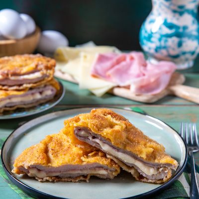 Cordon bleu impanato e fritto, tagliato a meta per rivelare prosciutto e formaggio filante