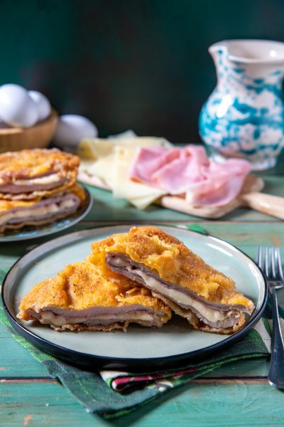 Cordon bleu impanato e fritto, tagliato a meta per rivelare prosciutto e formaggio filante