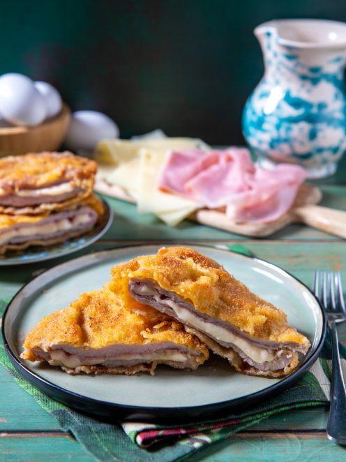 Cordon bleu impanato e fritto, tagliato a meta per rivelare prosciutto e formaggio filante