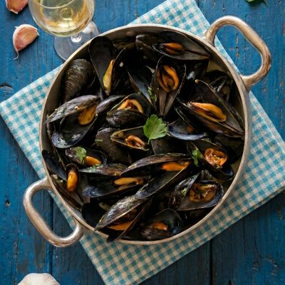 Cozze alla marinara aperte in padella, guarnite con prezzemolo fresco