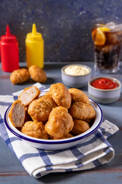 Nuggets di pollo fritti dorati in ciotola, uno spezzato mostra l'interno morbido