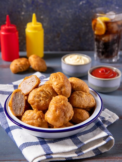 Nuggets di pollo fritti dorati in ciotola, uno spezzato mostra l'interno morbido