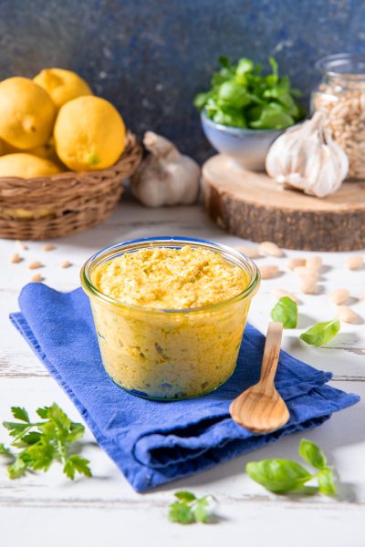 Pesto di limoni in vasetto con pinoli, aglio e foglie di basilico intorno